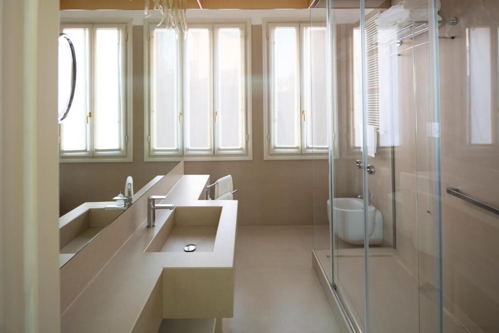 A modern bathroom with a large mirror, a sink, and a glass-enclosed shower.