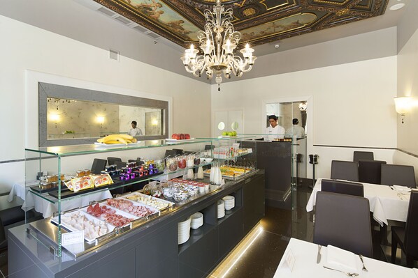 Un espace buffet proposant divers plats, une vitrine réfrigérée et un lustre.