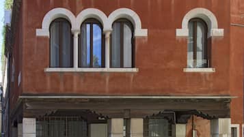A red building with arched windows and a balcony.