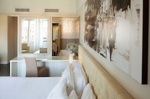 A hotel room with a bed, a desk, and a large framed picture on the wall.