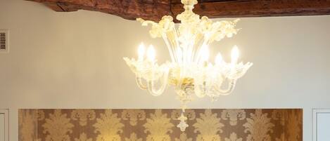 A bedroom with a tufted headboard, a chandelier, and bedside lamps.