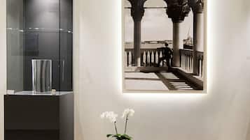 Ein modernes Interieur mit einer Glasvitrine, einer schwarzen Bank mit Blumenvasen und einem gerahmten Foto an der Wand.