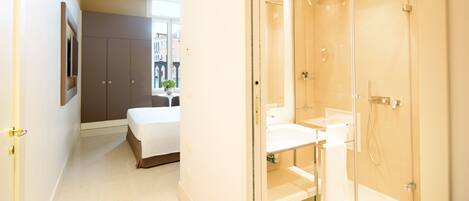 Un baño moderno con cabina de ducha de vidrio, un lavabo blanco y un espejo grande.