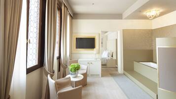 A hotel room with a bed, a desk, a chair, a TV, and a bathroom.