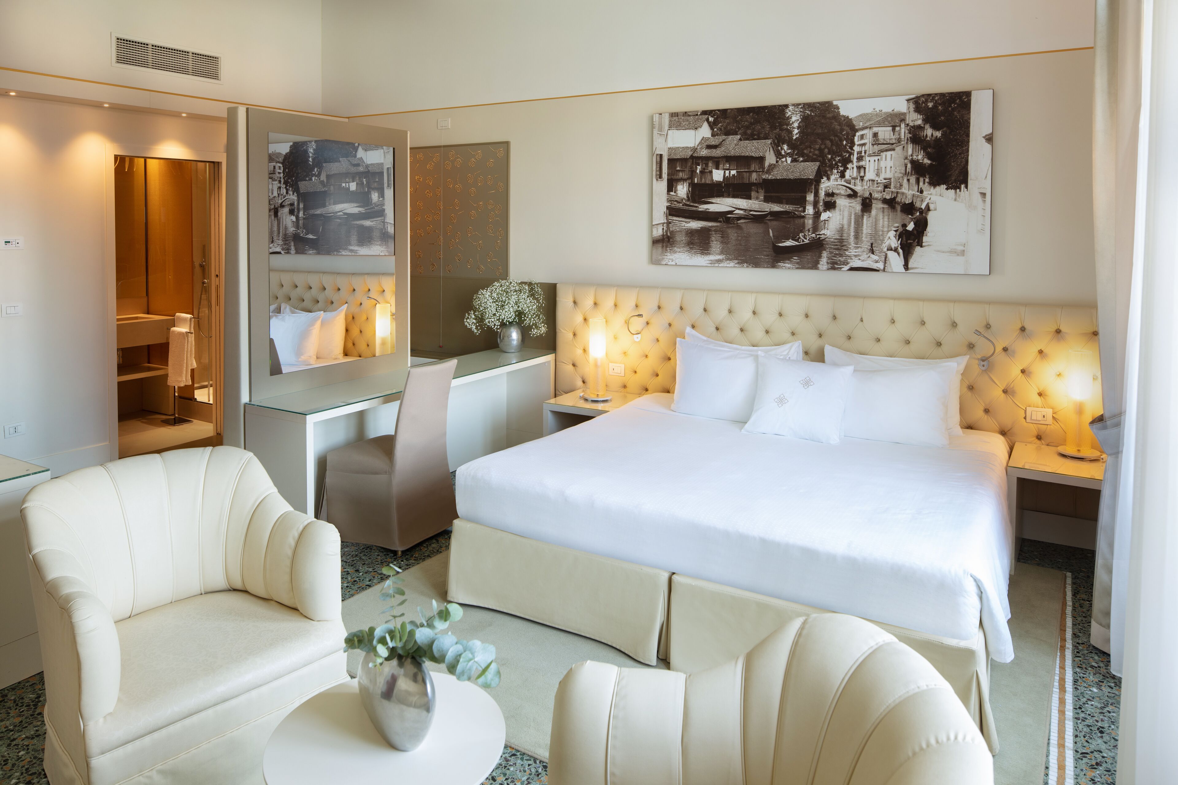 A hotel room with a large bed, a desk, a chair, and a sofa.