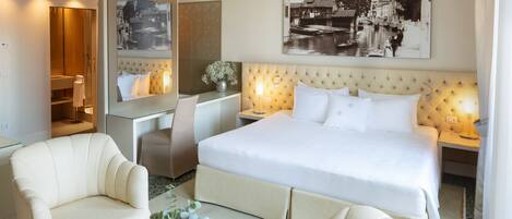 Quarto de hotel com uma cama grande, uma mesa, uma cadeira e um sofá.