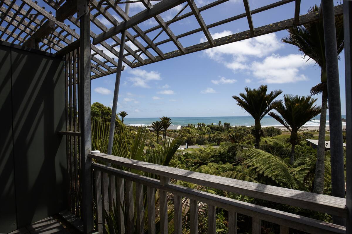 Ein Holzbalkon mit Blick auf das Meer und Palmen.
