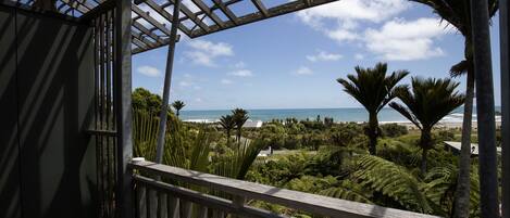 Ein Holzbalkon mit Blick auf das Meer und Palmen.