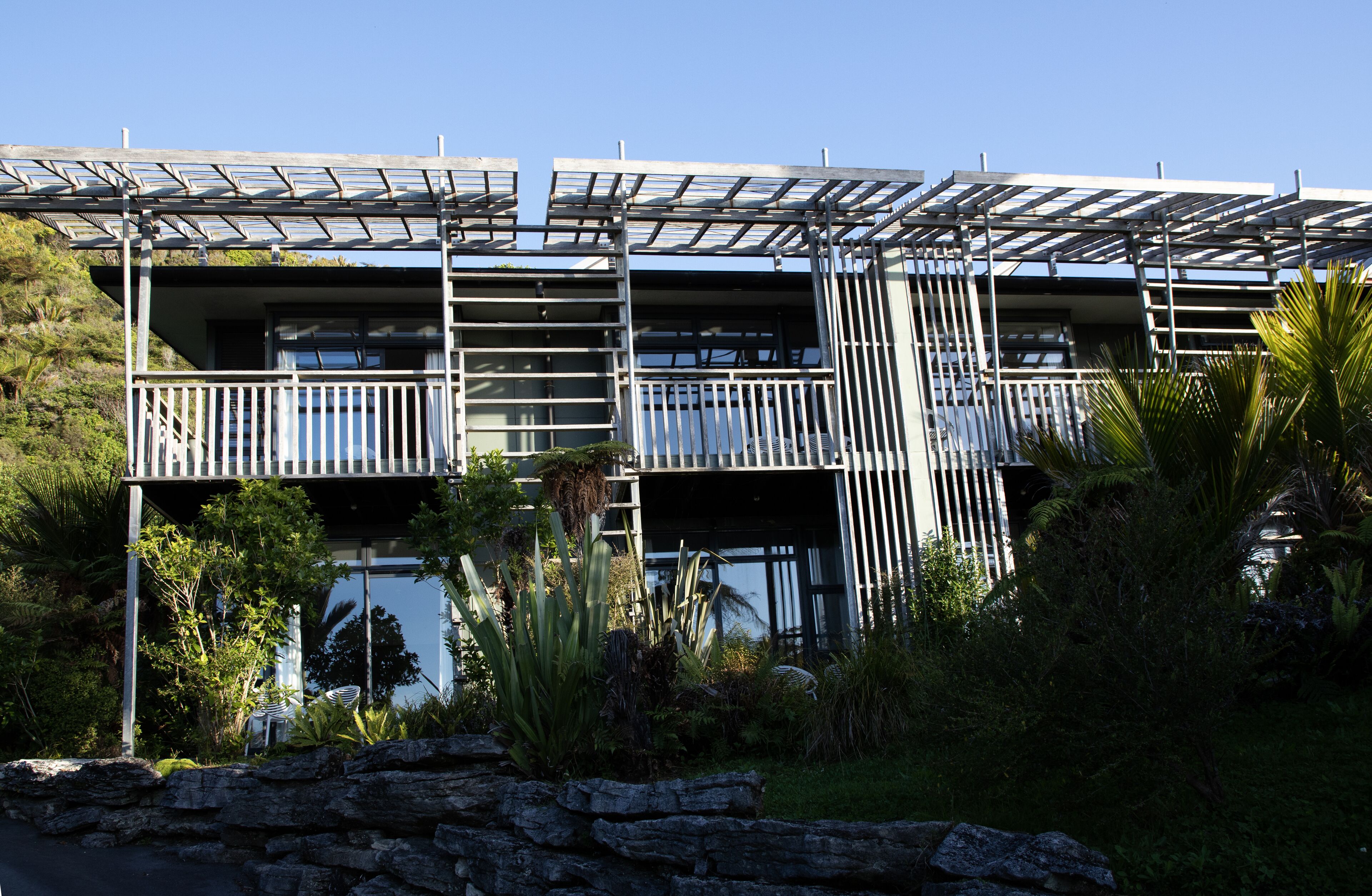 A modern building with a balcony and a stone wall in the foreground.