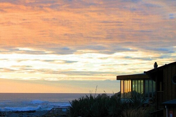 Un edificio costero con un amplio ventanal de vidrio, con vista al océano.