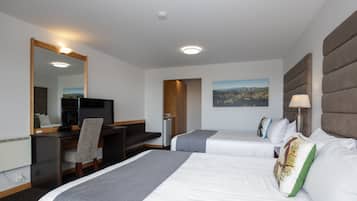A hotel room with two beds, a desk, a chair, a TV, and a large mirror.