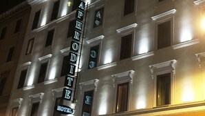 Un hotel de varios pisos con señalización iluminada que dice "APHRON HOTEL".