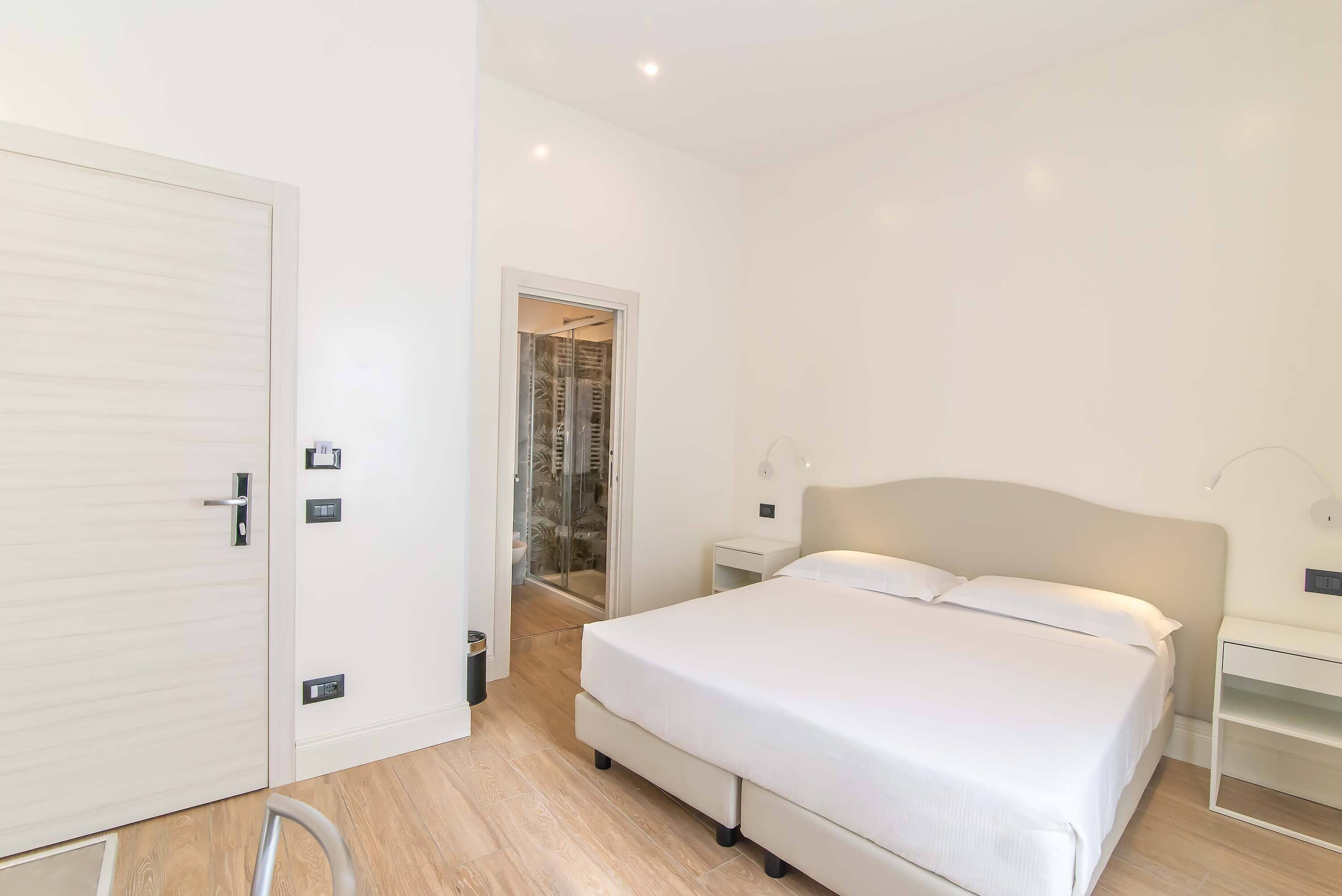 Un dormitorio con cama, mesitas de noche, armario y zona de ducha.