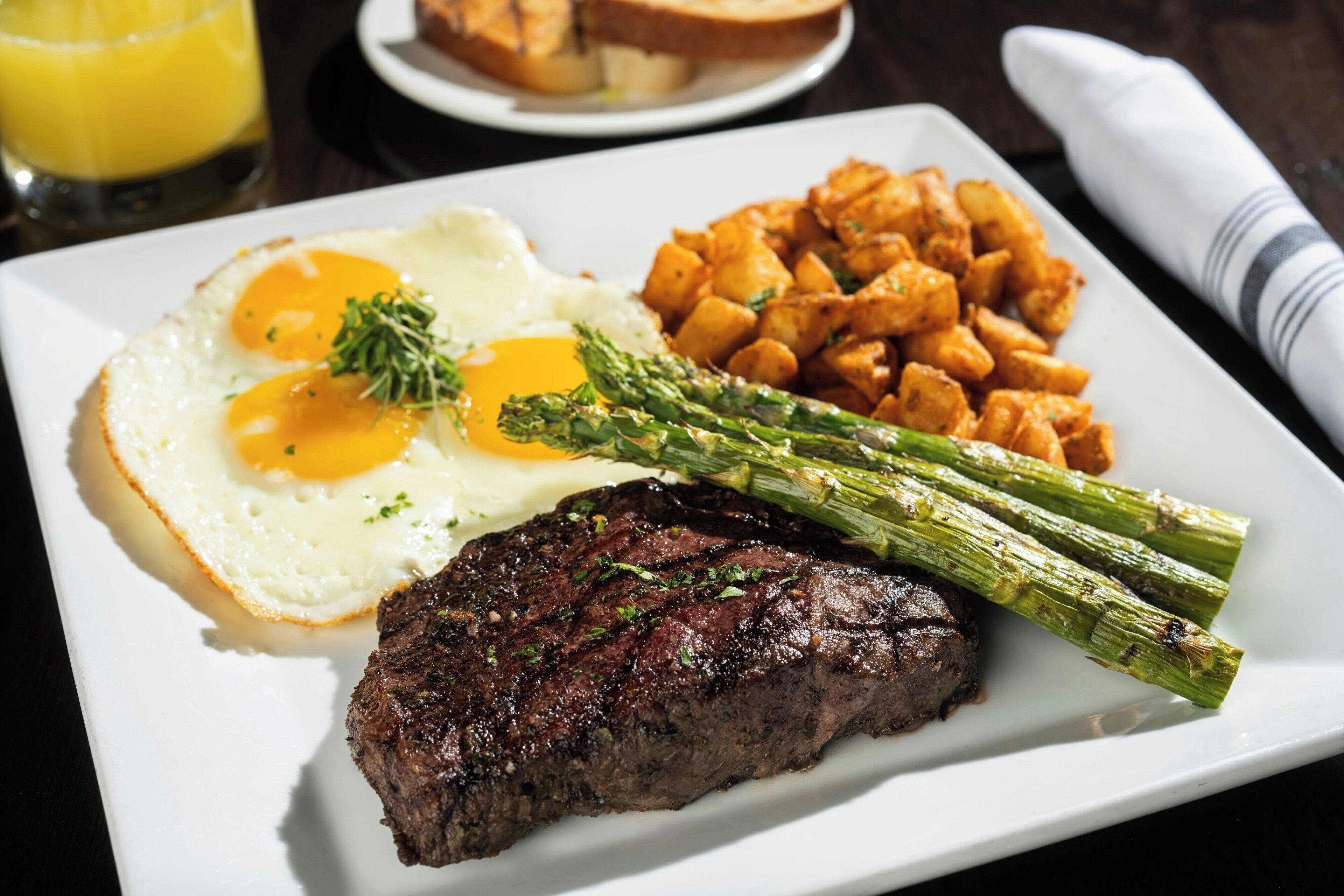 A plate with steak, eggs, asparagus, and potatoes.