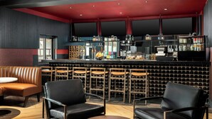 A bar area with leather seating, a counter with various beverages, and a wine rack. - Courtyard by Marriott Houston Rice University (Houston)