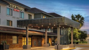 A Courtyard Marriott hotel with a covered entrance, outdoor seating, and a landscaped courtyard. - Courtyard by Marriott Houston Rice University (Houston)