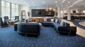 A modern lounge area with sofas, a coffee table, and a bar area with stools. - Courtyard by Marriott Ewing Princeton (Trenton)