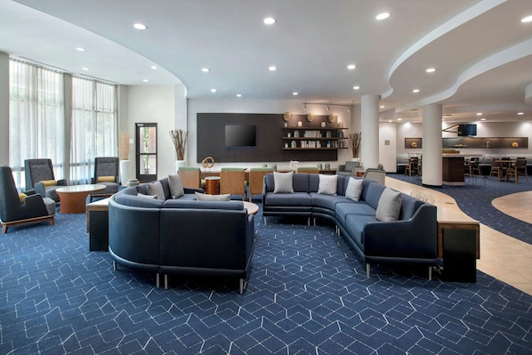 A modern lounge area with sofas, a coffee table, and a bar area with stools.