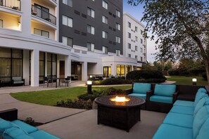 A hotel courtyard with outdoor seating, a fire pit, and a well-maintained lawn. - Courtyard by Marriott Ewing Princeton (Trenton)