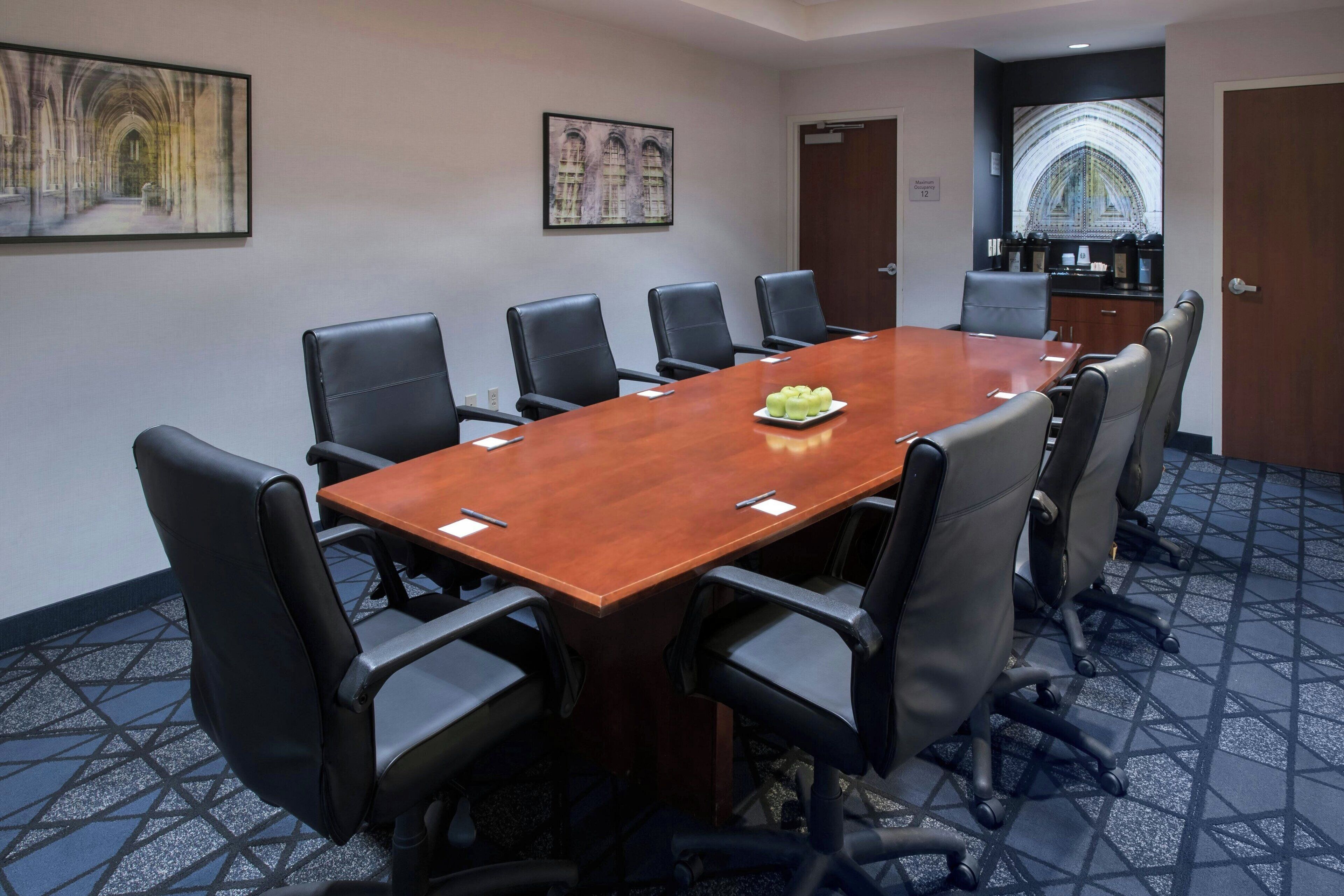 A conference room with a long table, eight chairs, and a small plate of fruit on the table.