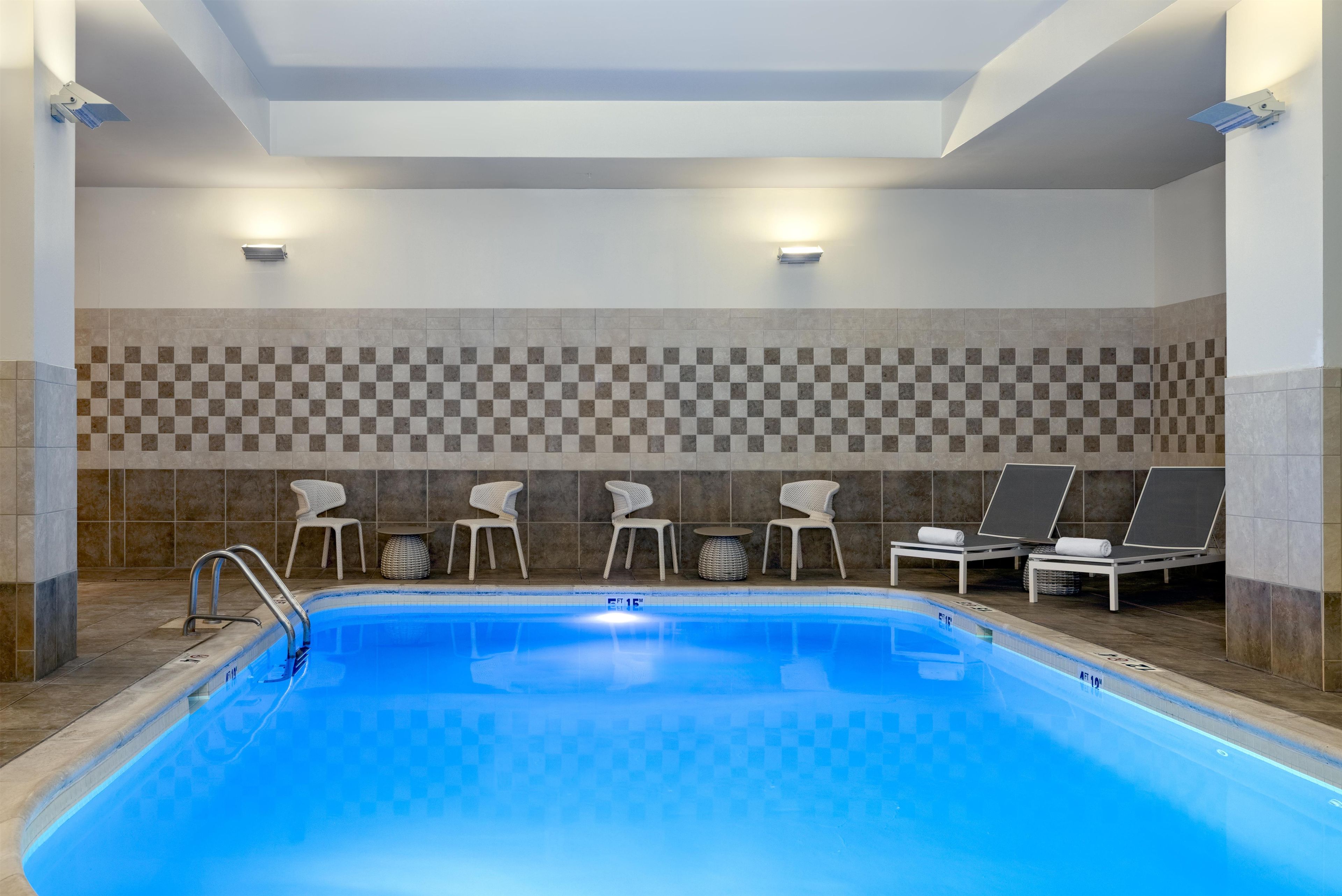 Una piscina con sillones de descanso y una pared a cuadros.