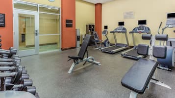 A gym with exercise equipment, a clock, and a sign indicating the fitness center.