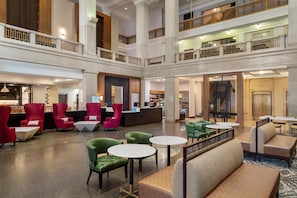 A spacious lobby with multiple seating areas, a reception desk, and a staircase connecting the floors. - Hilton Garden Inn Indianapolis Downtown (Indianapolis)