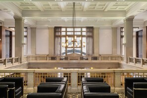A grand hall with a high ceiling, a chandelier, and a large window with curtains. - Hilton Garden Inn Indianapolis Downtown (Indianapolis)