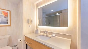 A modern bathroom with a large mirror, a sink, and a toilet.