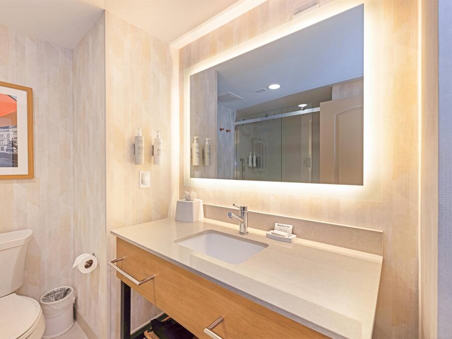 A modern bathroom with a large mirror, a sink, and a toilet.