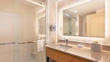 A modern bathroom with a glass shower enclosure, a vanity with a sink, and a large mirror.