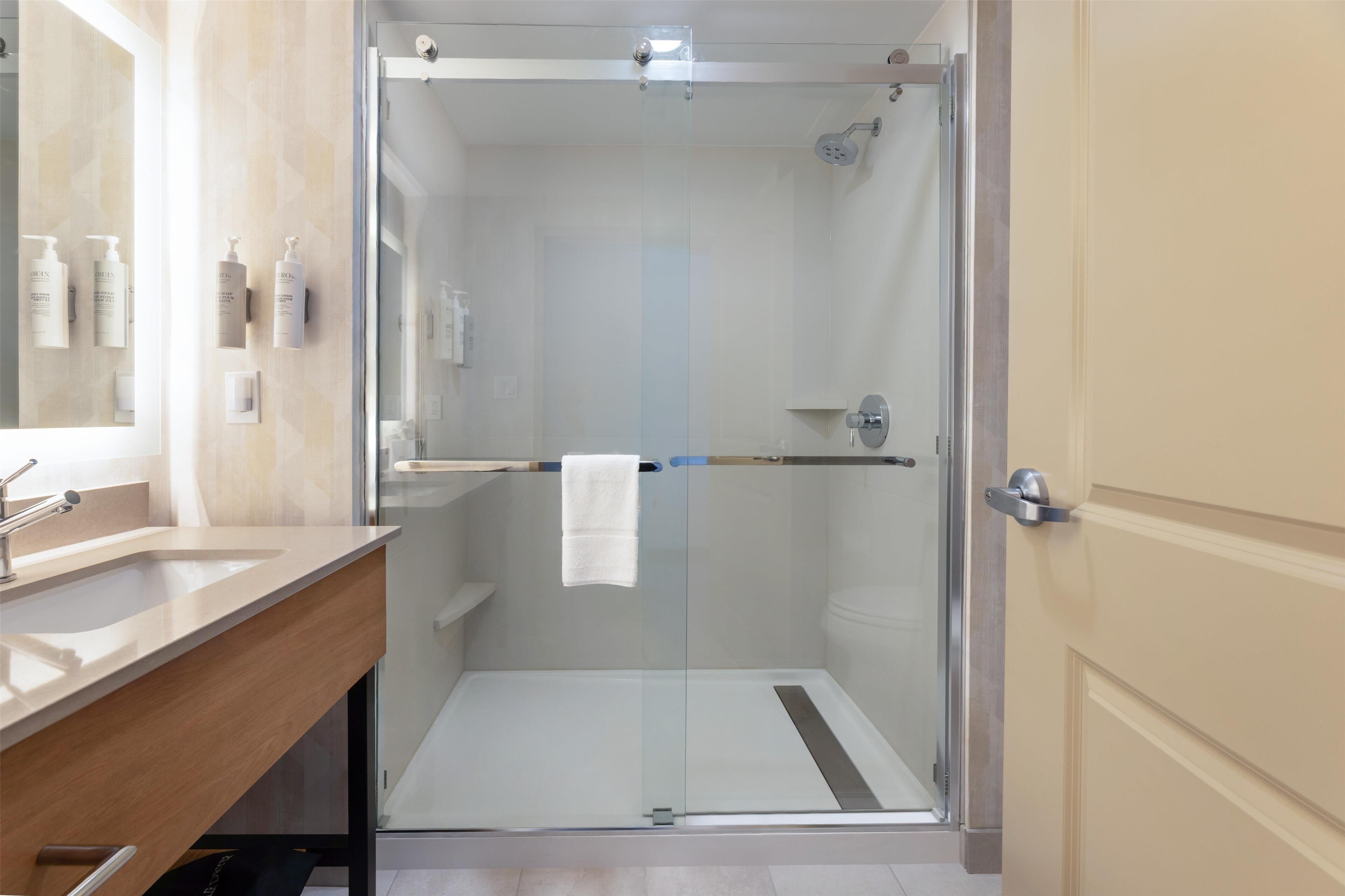 A modern bathroom with a glass-enclosed shower, a wooden vanity, and a large mirror.