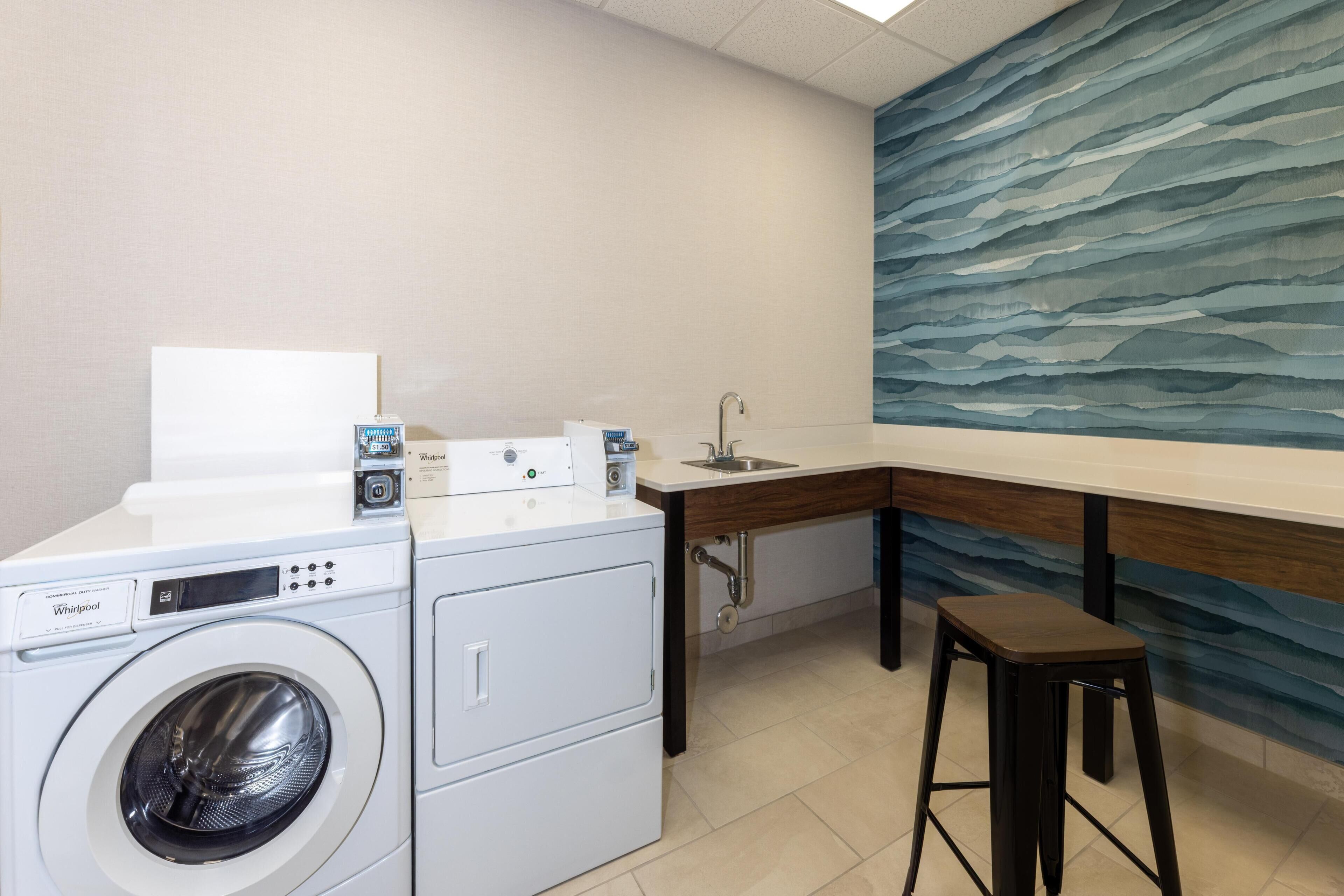 Un lavadero con lavadora Whirlpool, un lavamanos y una encimera de madera.
