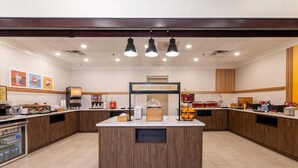 Un comedor con isla central, electrodomésticos de cocina y un letrero que indica servicio de desayuno.