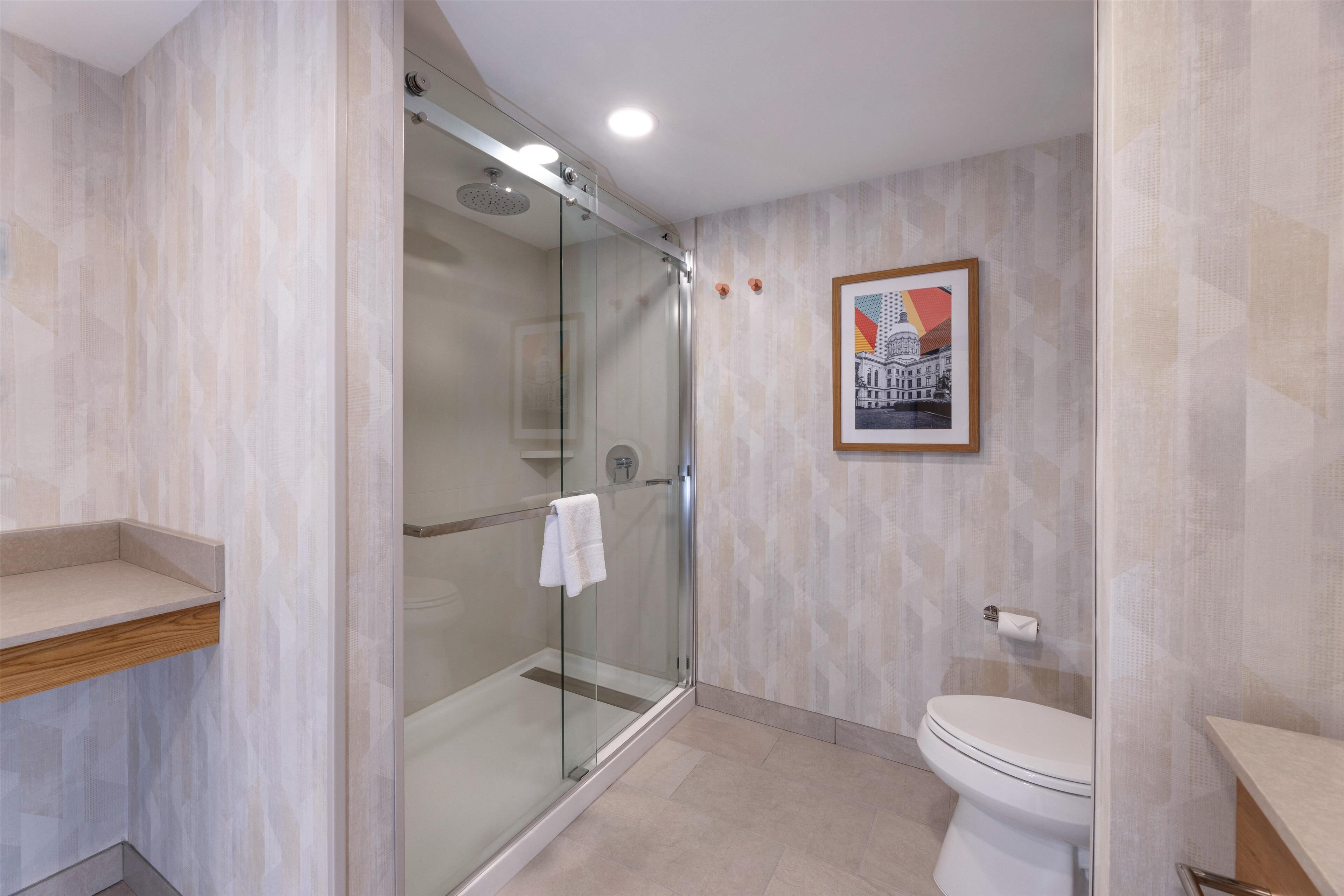 Une salle de bain moderne avec une douche à parois de verre, des toilettes et un tableau encadré au mur.