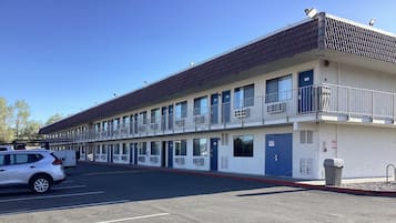 A motel with multiple rooms, a parking lot, and a trash bin.