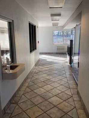 A hallway with tiled flooring, a window, and a wall-mounted air conditioning unit. - Motel 6 Reno, NV - Livestock Events Center (Reno)
