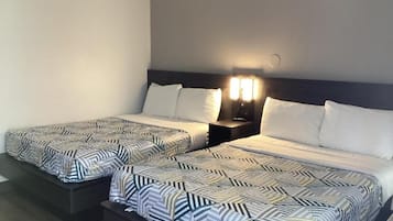A hotel room with two beds, each with patterned bedding and a nightstand with a lamp.
