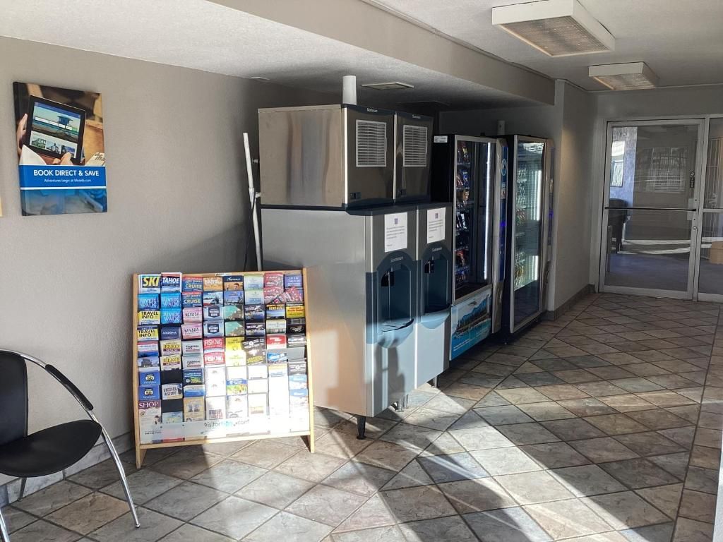 Un couloir comprenant un réfrigérateur, un distributeur automatique et un panneau d’affichage où sont accrochées des brochures de voyage.