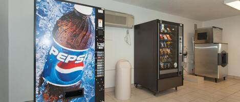 Una máquina expendedora con el logotipo de Pepsi, un refrigerador lleno de refrigerios y un microondas.