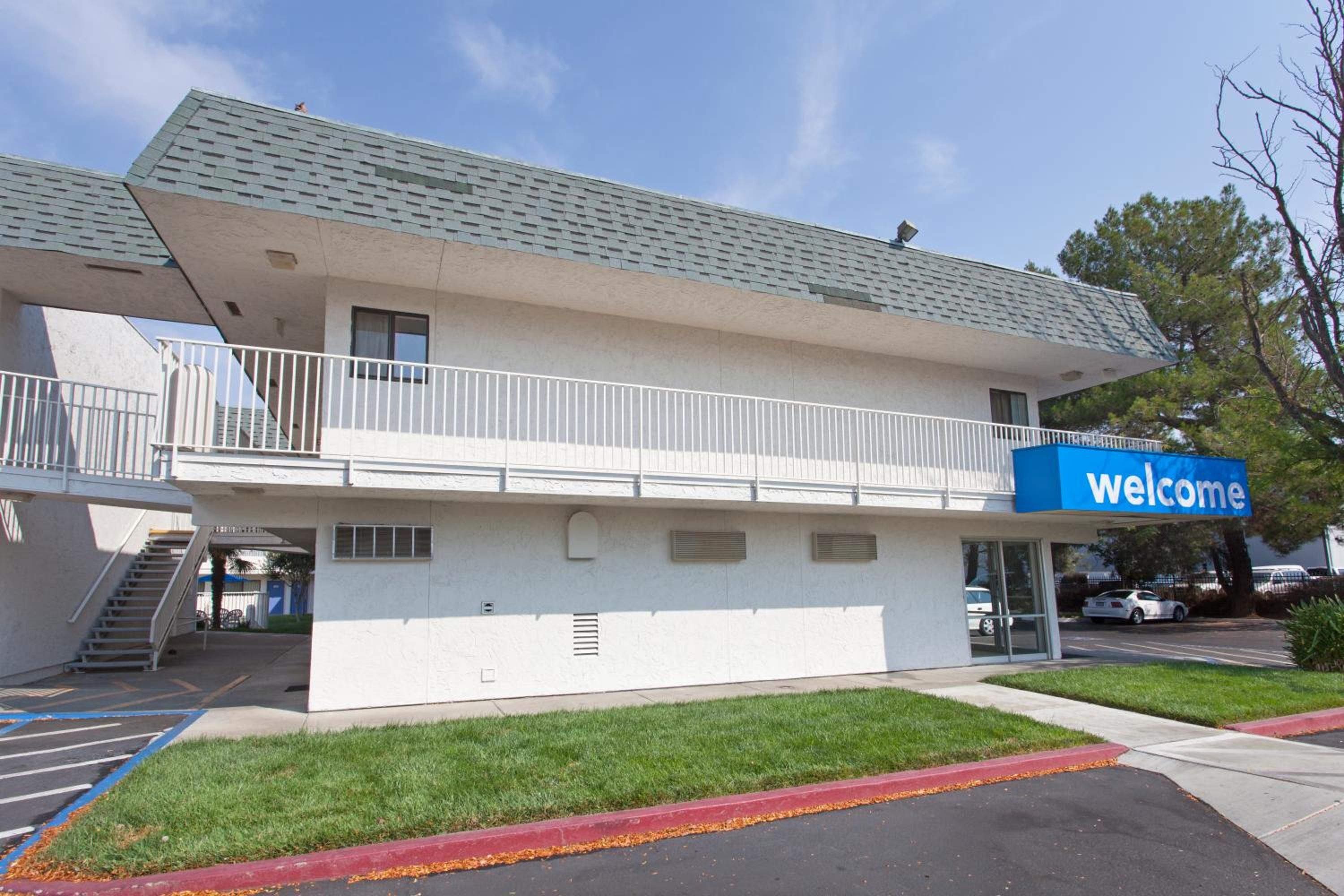 A two-story building with a 'Welcome' sign, a covered entrance, and a parking lot.