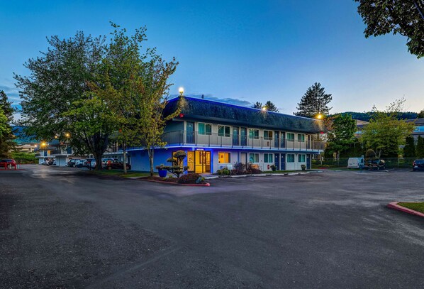 A motel with a blue exterior, multiple windows, and a parking lot.