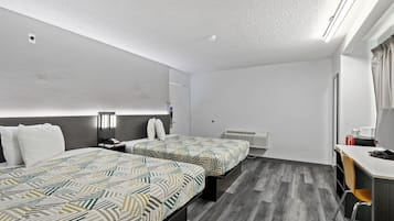 Habitación de hotel con dos camas, un escritorio, una silla, un espejo y una ventana.