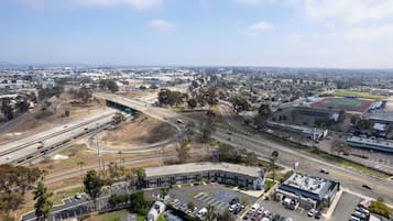 Uma estrutura de estacionamento em vários níveis, com um pátio central, rodeada por uma área comercial, um edifício grande e um campo de esportes.