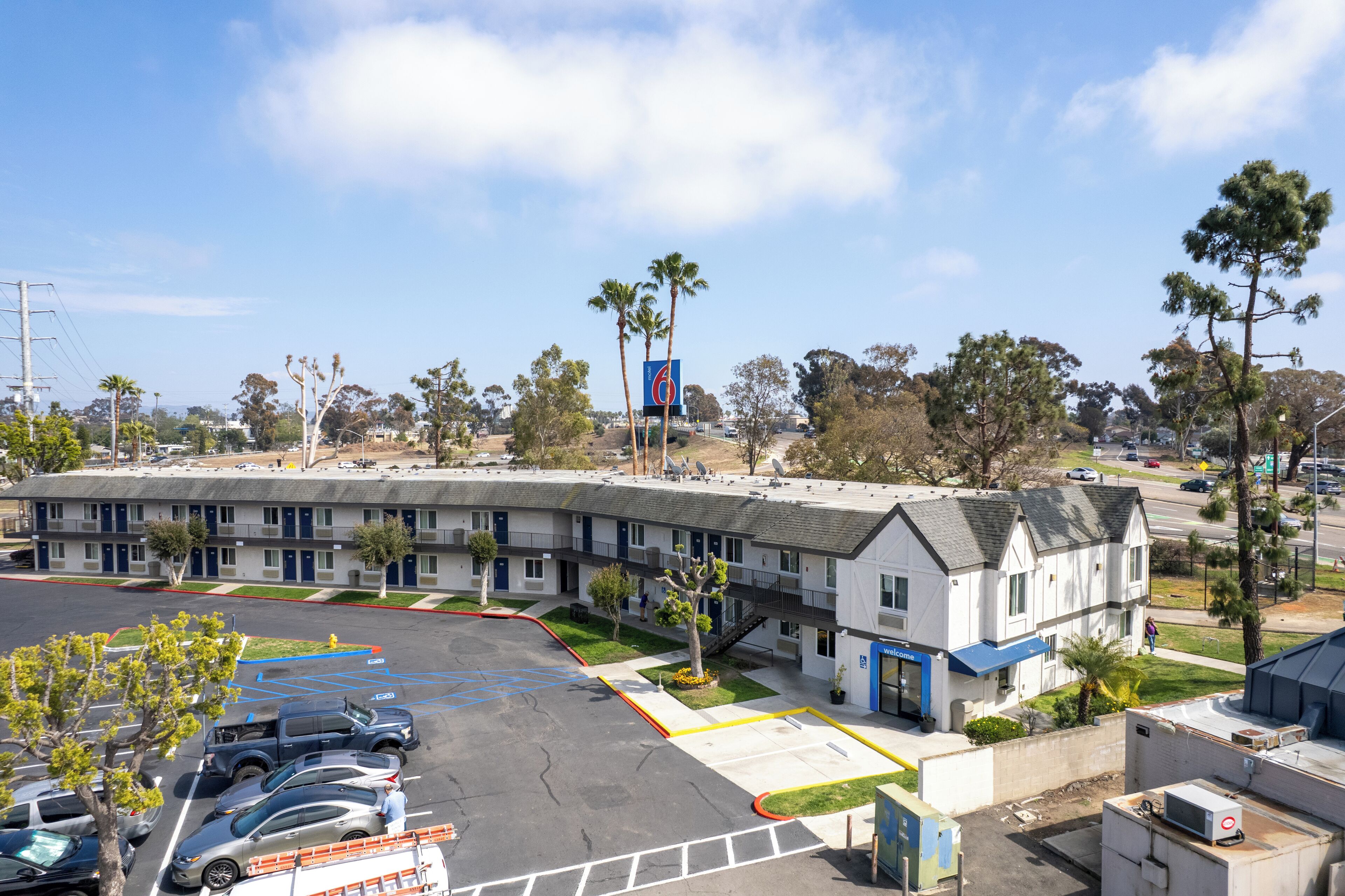 A motel with a parking lot, multiple buildings, and trees.