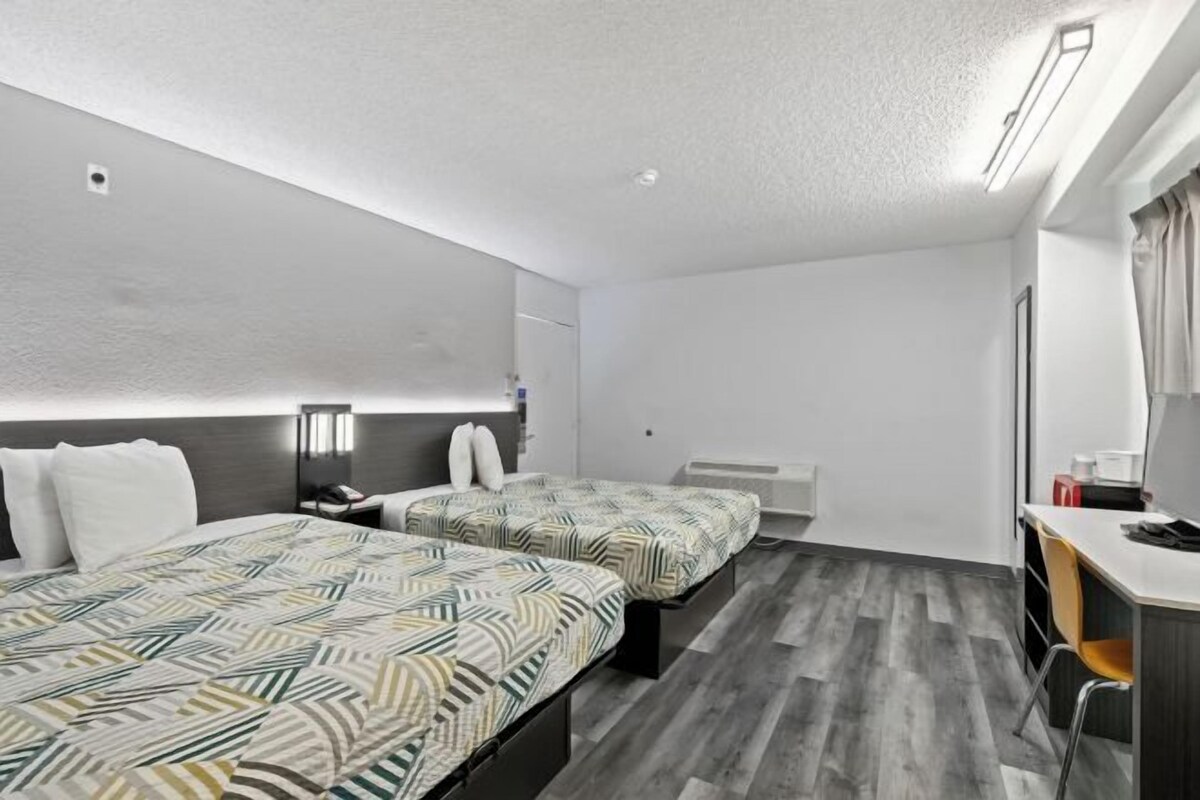 A hotel room with two beds, a desk, and a chair.