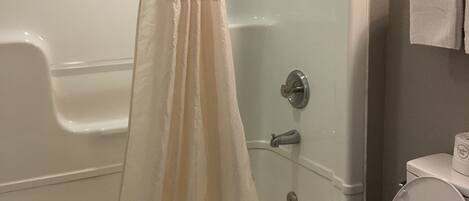 A bathroom with a bathtub, shower, and toilet.