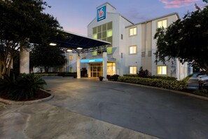 A modern hotel with a prominent '6' sign, a covered entrance, and well-maintained landscaping. - Motel 6 Orlando, FL - International Dr (Orlando)