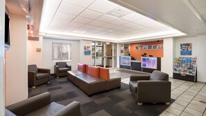 A lobby with seating, a reception desk, and informational posters. - Motel 6 Orlando, FL - International Dr (Orlando)