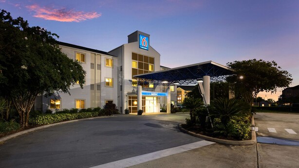 A modern hotel with a '6' logo, a covered entrance, and a landscaped driveway. - Motel 6 Orlando, FL - International Dr (Orlando)